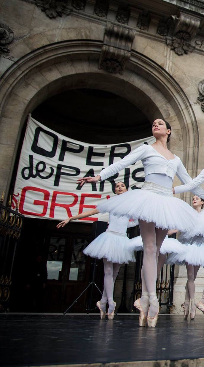 Danseuses de l’Opéra de Paris en pointes devant une banderole de grève.